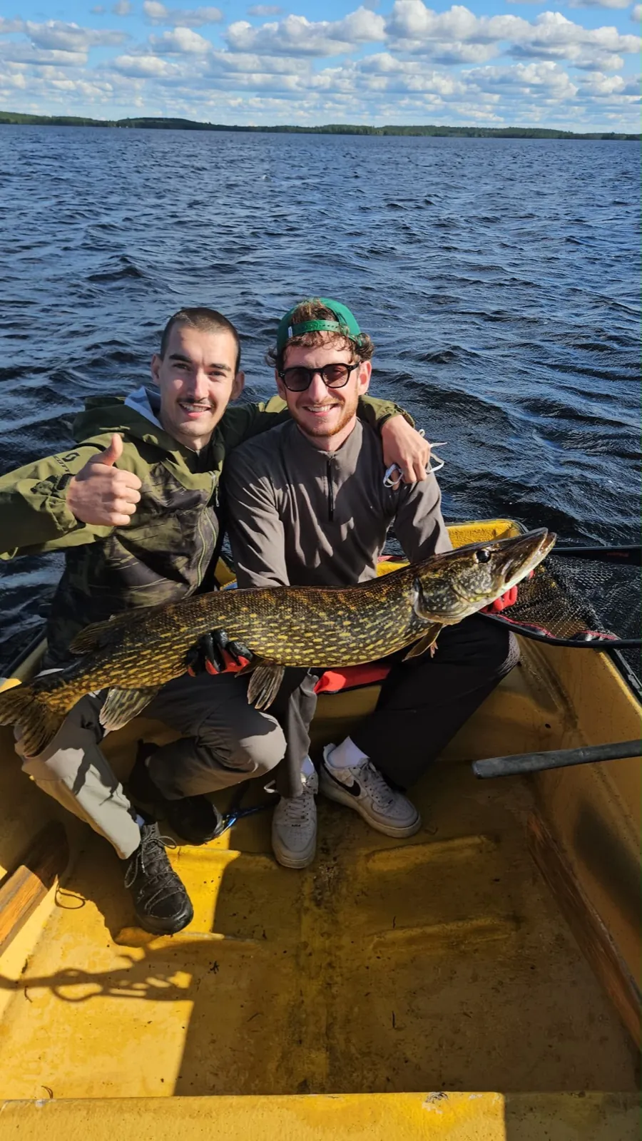 Dos pescadores sosteniendo un lucio grande en una barca