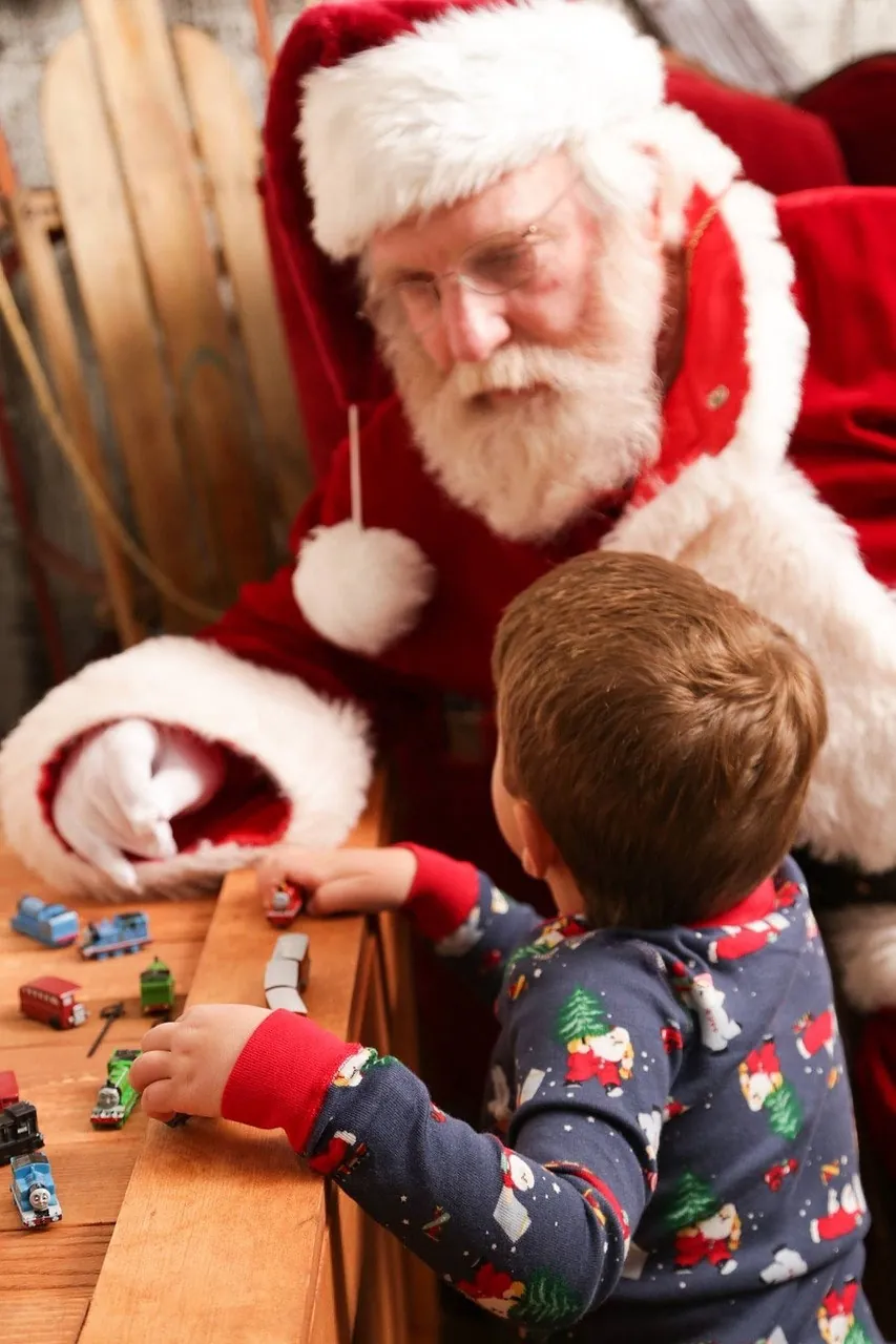 Niño conociendo a Papá Noel junto a una mesa