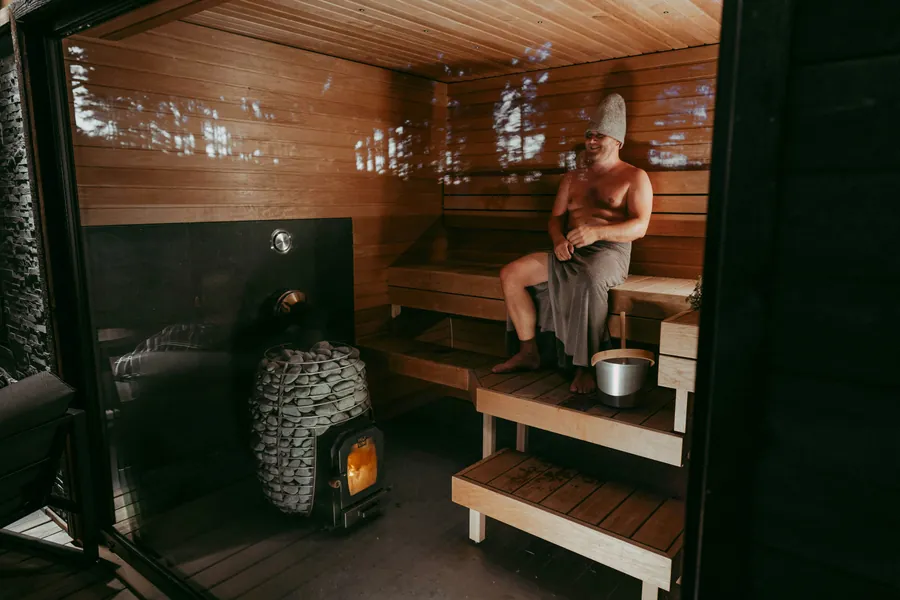 Persona en la sauna sobre un banco de madera junto a la estufa