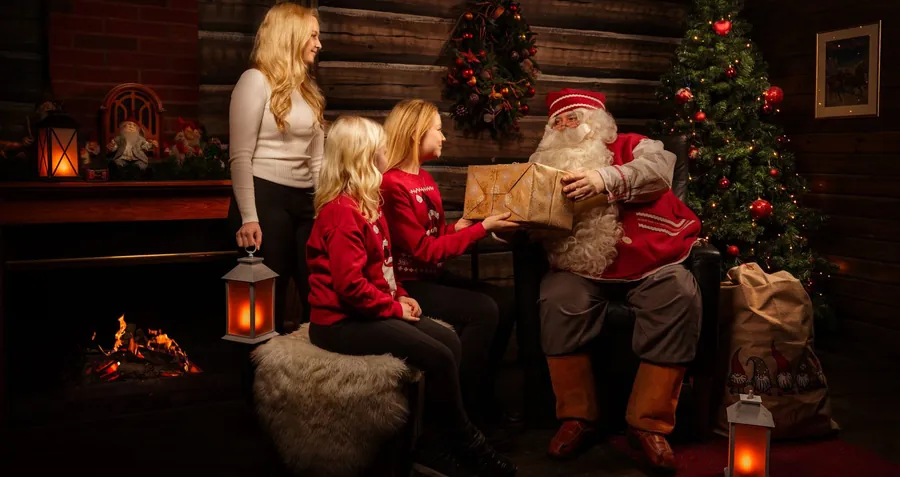 Familia visitando a Papá Noel en una habitación decorada para Navidad