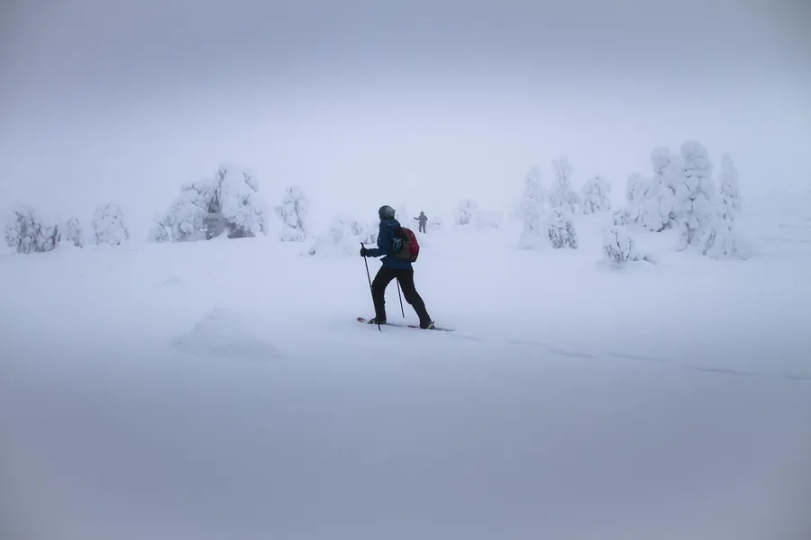 Persona che cammina in un paesaggio innevato e nebbioso