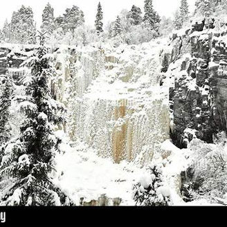 Cascada helada entre paredes rocosas nevadas