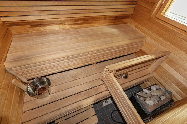 Banquettes et poêle de sauna dans une pièce lambrissée