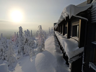 Cabaña nevada bajo un sol invernal bajo
