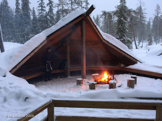 Refugio abierto de madera con fuego en la nieve