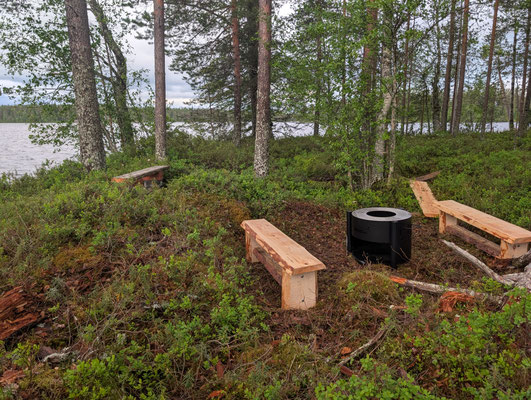 Bancs en bois et foyer entre les arbres au bord du lac