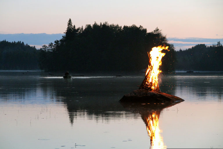 Fire burning on a small platform in the lake at dusk