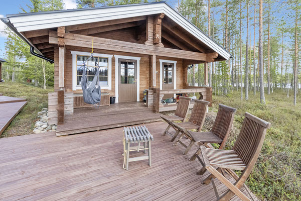 Maison en bois avec grandes fenêtres et chaises sur la terrasse