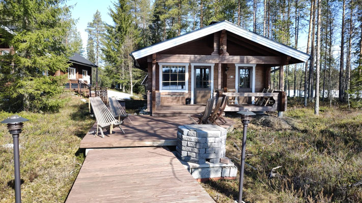 Passerelle en bois menant à une petite maison parmi les arbres