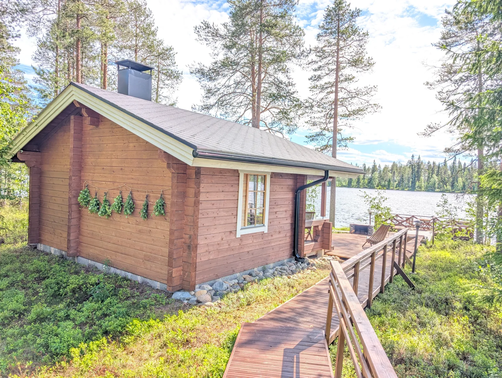 Strandsauna mit Birkenzweigen und Holzsteg im Sommer