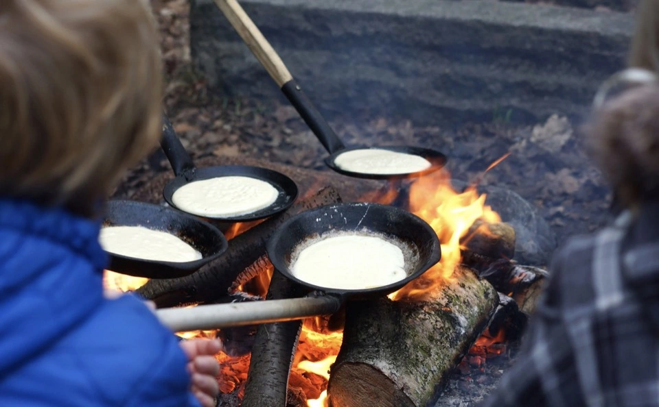 Pfannkuchen werden in Pfannen über dem Feuer gebacken