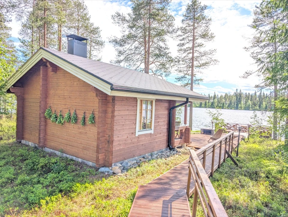 Saunahaus mit Birkenzweigen an der Wand und Blick zum See