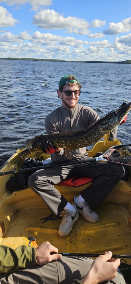 Angler mit einem gefangenen Hecht im Boot