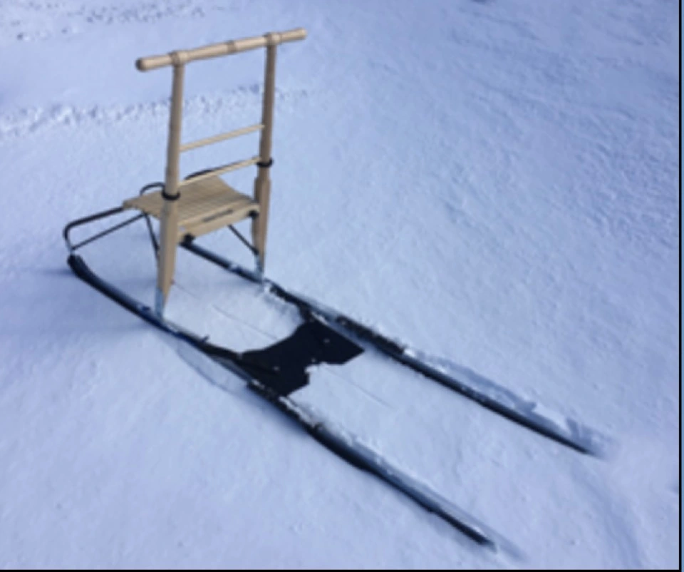 Tretschlitten mit Holzsitz auf einer Schneefläche