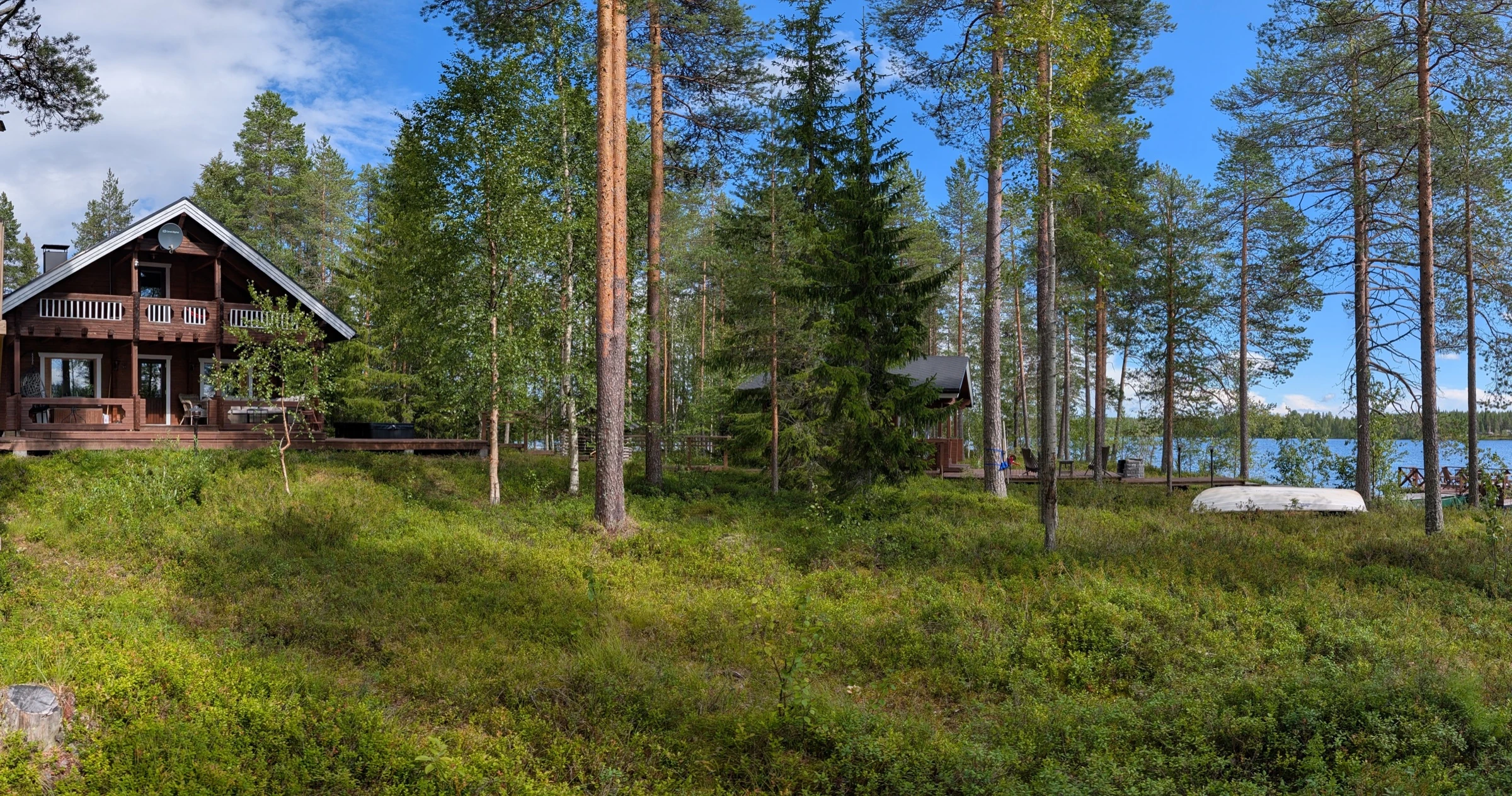 Das Haupthaus zwischen Kiefern am See im Sommer